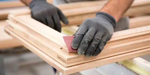 Tischler schleift hölzernen Fensterrahmen in der Werkstatt – präzise Handarbeit von Jan Flieger