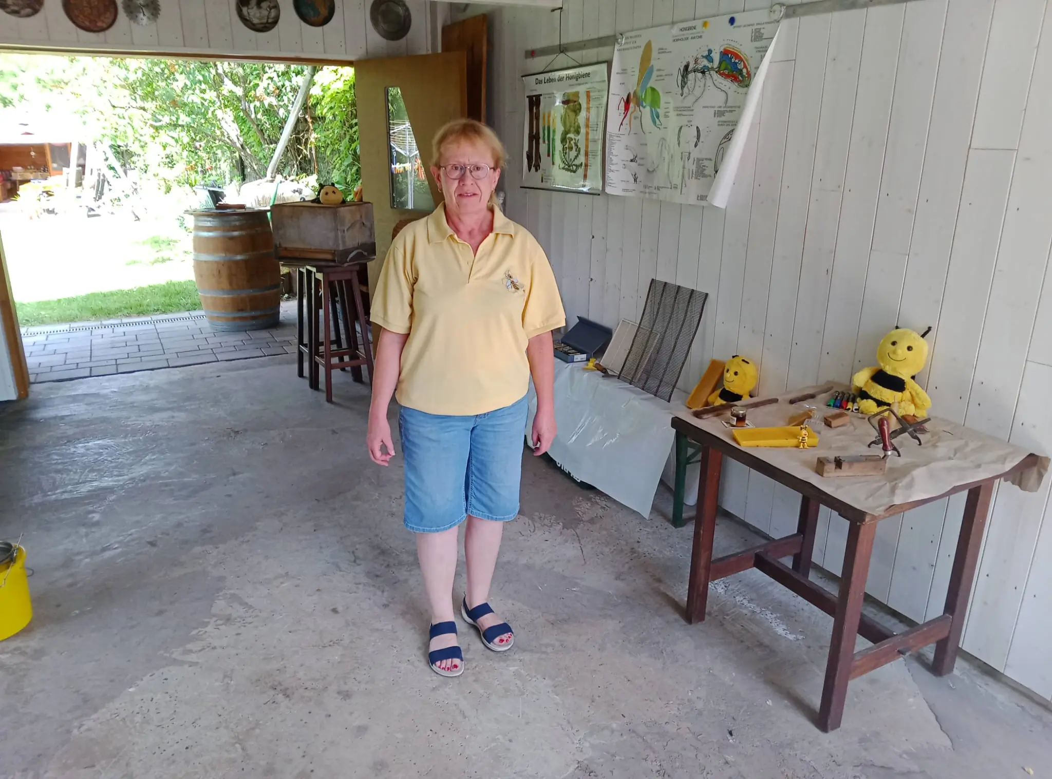Frau Flieger steht im Imkerhaus vor Lehrmaterialien und Imkereiausrüstung.