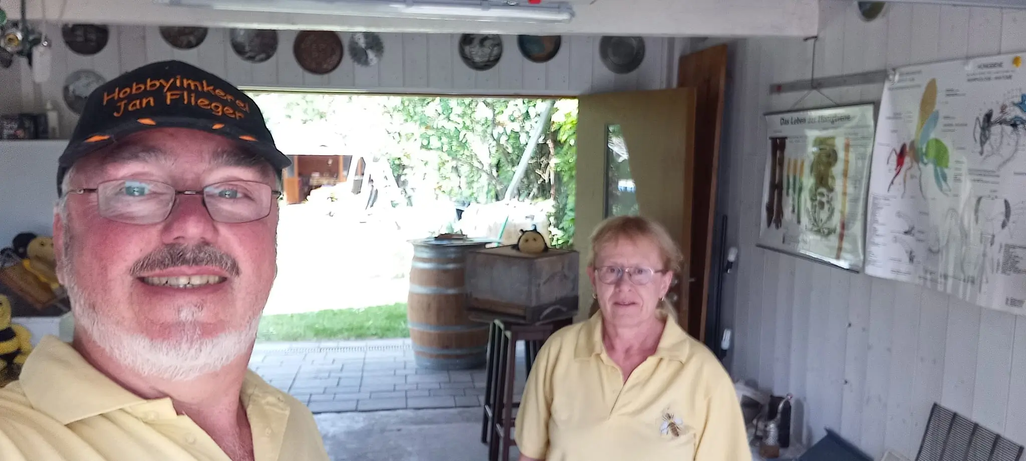Imker Jan Flieger und seine Partnerin stehen in ihrer Imkerei vor Lehrpostern und Ausrüstung.