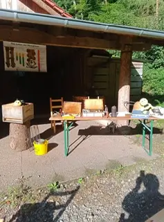 Ausstellungstisch mit Imkereigeräten, Wabenrahmen und Bienenstöcken bei einer Imkerführung.