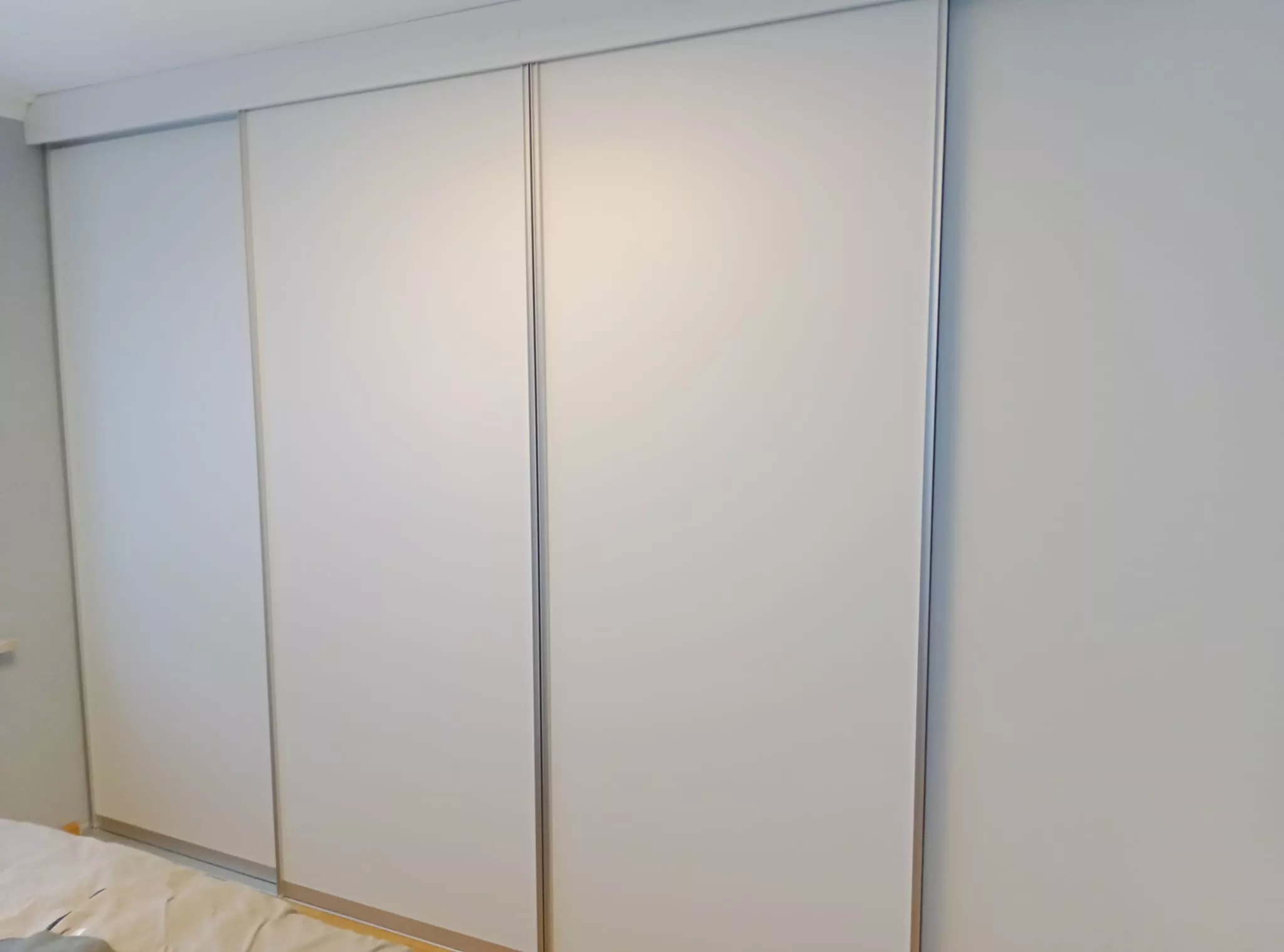 Geschlossener, moderner Einbauschrank mit weißen Schiebetüren – maßgefertigt