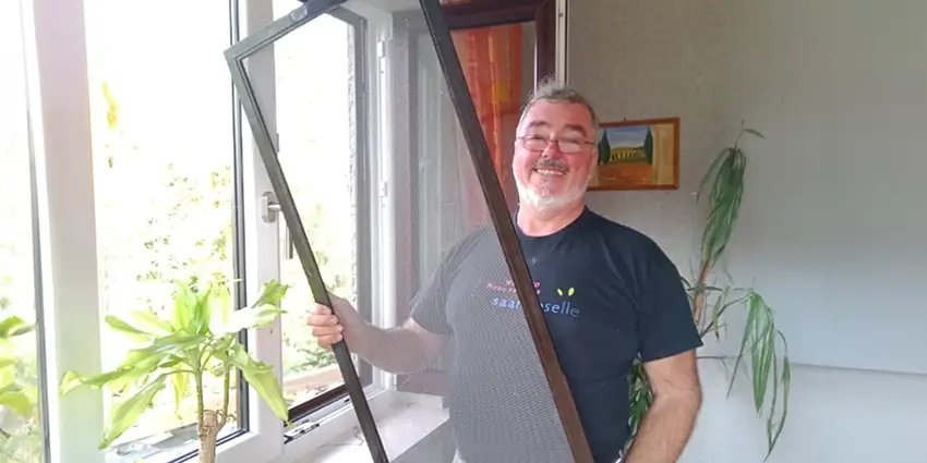 Jan Flieger hält ein neues Fliegengitter für das Fenster in der Hand